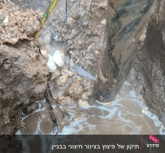 צינור מים דולף בתוך בור בוצי